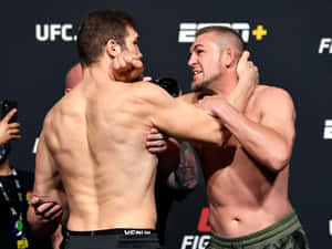 Two shirtless MMA fighters locked in a grappling stance at a UFC event. — Fight Wallpaper