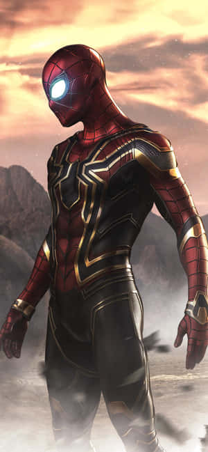Spider-Man in red gold and black suit standing heroically in a rocky landscape at sunset. — iPhone 13 Pro Max Wallpaper