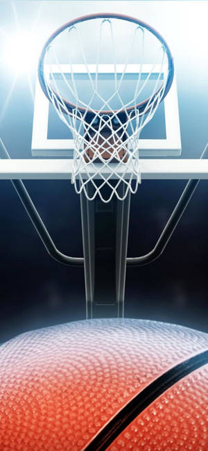 A basketball about to pass through a hoop with bright overhead lighting. — iPhone 13 Pro Max Wallpaper