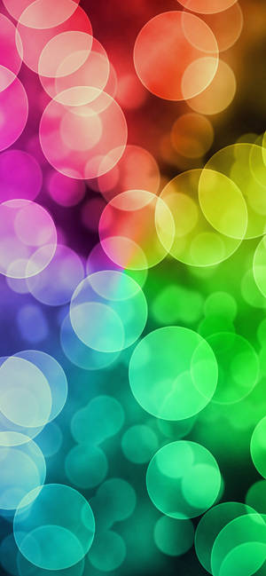 Soft glowing circles in rainbow colors create a dreamy abstract background. — iPhone 13 Pro Max Wallpaper