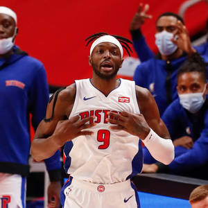 Basketball player in Pistons jersey gesturing during game with masked teammates in background. — Best Wallpaper