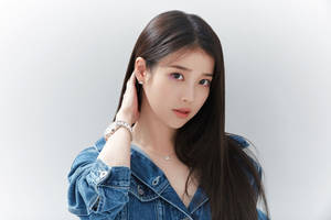 Junge Frau in Jeansjacke posiert mit der Hand am Ohr. — Iu Wallpaper