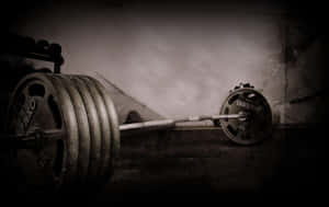 Heavy barbell with weights on dark gym floor under dramatic lighting — Barbell Wallpaper