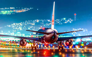 Un grande aereo su una pista bagnata di notte con luci della città che brillano sullo sfondo. — Luci Sfondi