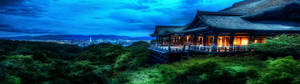 Gammelt japansk tempel oplyst ved skumringstid med udsigt over en by. — Monitor Background