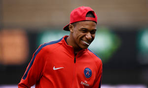 Footballer laughing in red PSG training gear during practice. — Mbappe Wallpaper