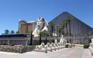 Egyptian-themed hotel with sphinx and pyramid in desert setting. — Hotel Wallpaper