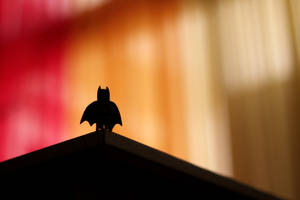 Figura LEGO Batman em silhueta em um telhado contra fundo quente desfocado — Super-herói Papéis de Parede
