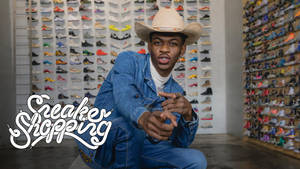 Jonge man in cowboyhoed en denim poserend in sneakerwinkel met kleurrijke schoenenmuren. — Nas Achtergronden