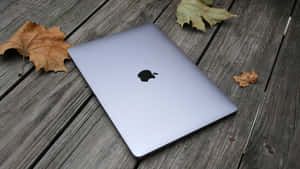 Zilveren MacBook op houten dek met herfstbladeren — Mac Achtergronden