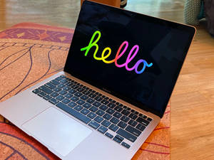 Ordinateur portable argent avec bonjour arc-en-ciel sur écran sur tapis à motifs. — MacBook Fonds d'écran