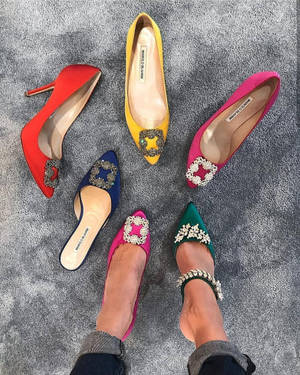 Cinco saltos altos coloridos com detalhes de joias dispostos em um tapete cinza. — Moda Papéis de Parede