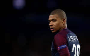 Football player Kylian Mbappe in maroon jersey looking over shoulder at stadium. — Mbappe Wallpaper
