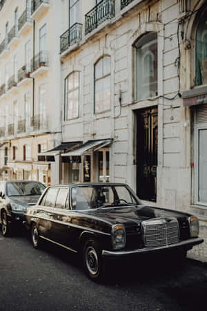 Mercedes preto vintage estacionado em uma rua histórica de cidade europeia ao pôr do sol. — Clássico Papéis de Parede