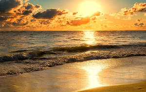 Sunset over ocean with waves washing onto sandy beach. — Glory Wallpaper