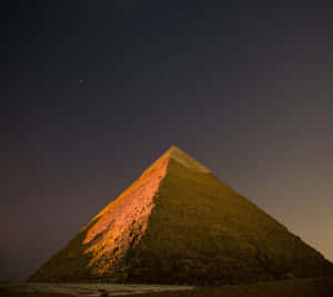 Pyramide ancienne brillant sous un ciel nocturne étoilé dans le désert — Image Fonds d'écran