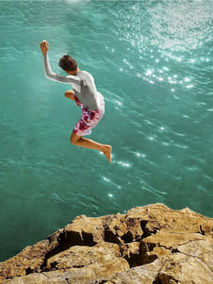Personne sautant d'une falaise dans l'eau turquoise — Image Fonds d'écran