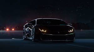 Black sports car with glowing headlights on a dark road under stars. — Lamborghini Wallpaper
