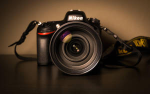 Een Nikon DSLR-camera met lens op donker houten oppervlak onder warm licht. — Camera Achtergronden