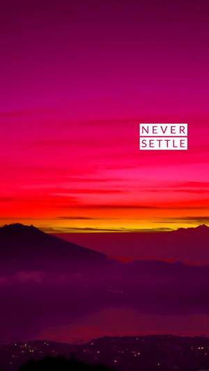 Tramonto vibrante magenta e arancione sopra montagne con luci della città sotto e sovrapposizione di testo. — OnePlus Sfondi