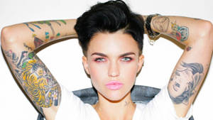 A tattooed woman with short hair and pink lips poses with arms raised. — Ruby Rose Wallpaper