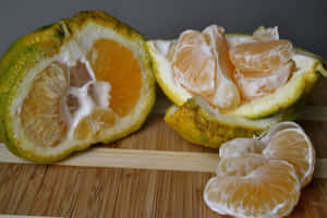 A peeled citrus fruit with segments on a wooden board. — Fruits Wallpaper