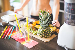 A pineapple on a cutting board with glasses and a blender for smoothies. — Fruits Wallpaper