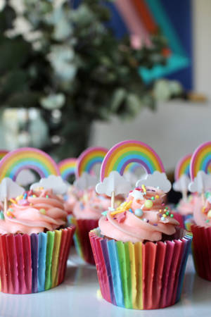 Cupcake colorati con involucri arcobaleno e topper arcobaleno su una superficie bianca. — Cupcake Sfondi