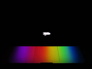 Apple-logo glødende over en regnbuefarvegradient på en mørk skærm. — Os baggrund Baggrunde