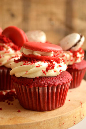 Cupcake al velluto rosso con glassa al formaggio cremoso e macarons su un tagliere di legno. — Cupcake Sfondi