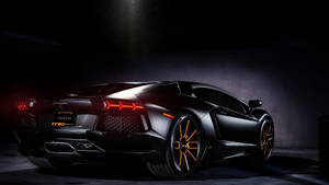 Black Lamborghini Aventador with orange wheels and taillights in a dark studio. — Lamborghini Wallpaper