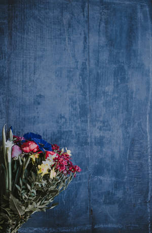 A colorful floral arrangement on a weathered blue wooden surface. — Redmi Wallpaper