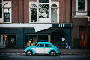 A turquoise and white vintage Volkswagen Beetle parked on a city street. — Retro Wallpaper