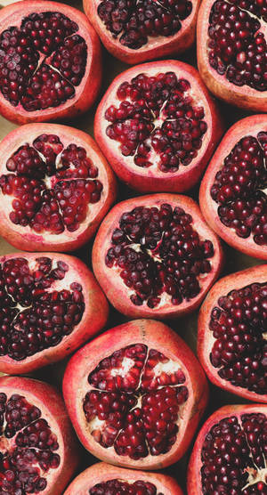 A dense arrangement of cut pomegranates showing their ruby-red seeds. — Fruit Wallpaper