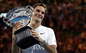 Roger Federer sorridente mentre tiene un grande trofeo d'argento di notte. — Federer Sfondi
