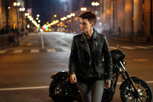 Person in leather jacket walking beside motorcycle on wet city street at night. — Ruby Rose Wallpaper