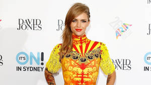 Woman in bold yellow orange dress with fringe sleeves at Sydney event. — Ruby Rose Wallpaper