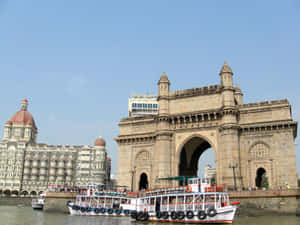 Monumento Gateway of India com barcos na água e Taj Mahal Hotel ao fundo. — Edifícios Papéis de Parede
