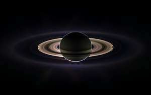 Saturn with its prominent rings illuminated in the void of space. — Saturn Wallpaper