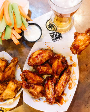 Buffalo Wings mit Sellerie, Karotten und Bier auf einem Restauranttisch. — Wild Wallpaper