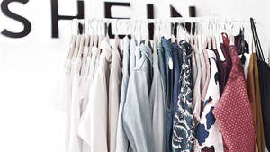 Perchero con varias prendas de vestir en un entorno de tienda minorista. — She Fondos de pantalla
