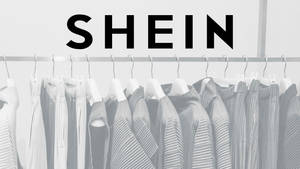 Logotipo de la marca SHEIN sobre el perchero con prendas plisadas en escala de grises. — She Fondos de pantalla