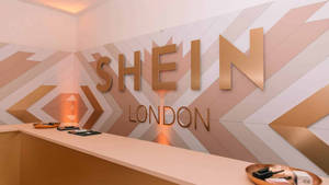 Recepción de la tienda Shein London con letras doradas y diseño de pared geométrica. — She Fondos de pantalla