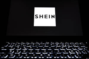Pantalla de portátil mostrando el logotipo de SHEIN con teclado brillante en habitación oscura — She Fondos de pantalla