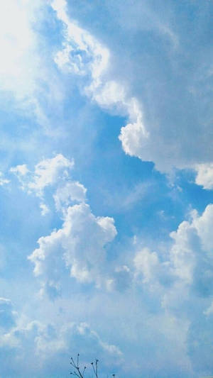 Blue sky with fluffy white clouds and sunlight filtering through — Blue Wallpaper