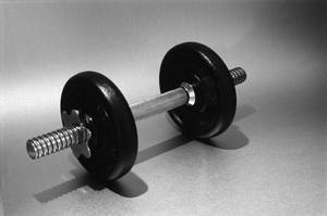 A black dumbbell with silver accents lies on a gray surface. — Barbell Wallpaper