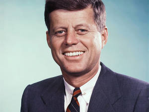 Porträt von John F Kennedy lächelnd in Anzug und Krawatte vor einem blauen Hintergrund. — F Wallpaper