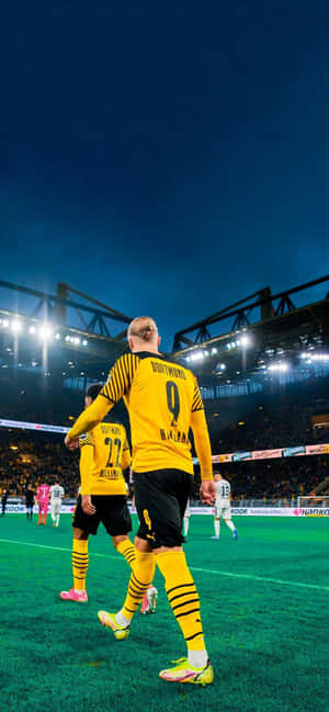 Two soccer players in yellow jerseys walking on a lit field at night. — Local Wallpaper