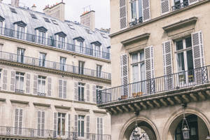 Parisian buildings with stone walls white shutters and black iron balconies. — Hotel Wallpaper