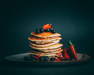 Pile de crêpes garnies de fraises et de myrtilles sur une assiette sombre. — Image Fonds d'écran